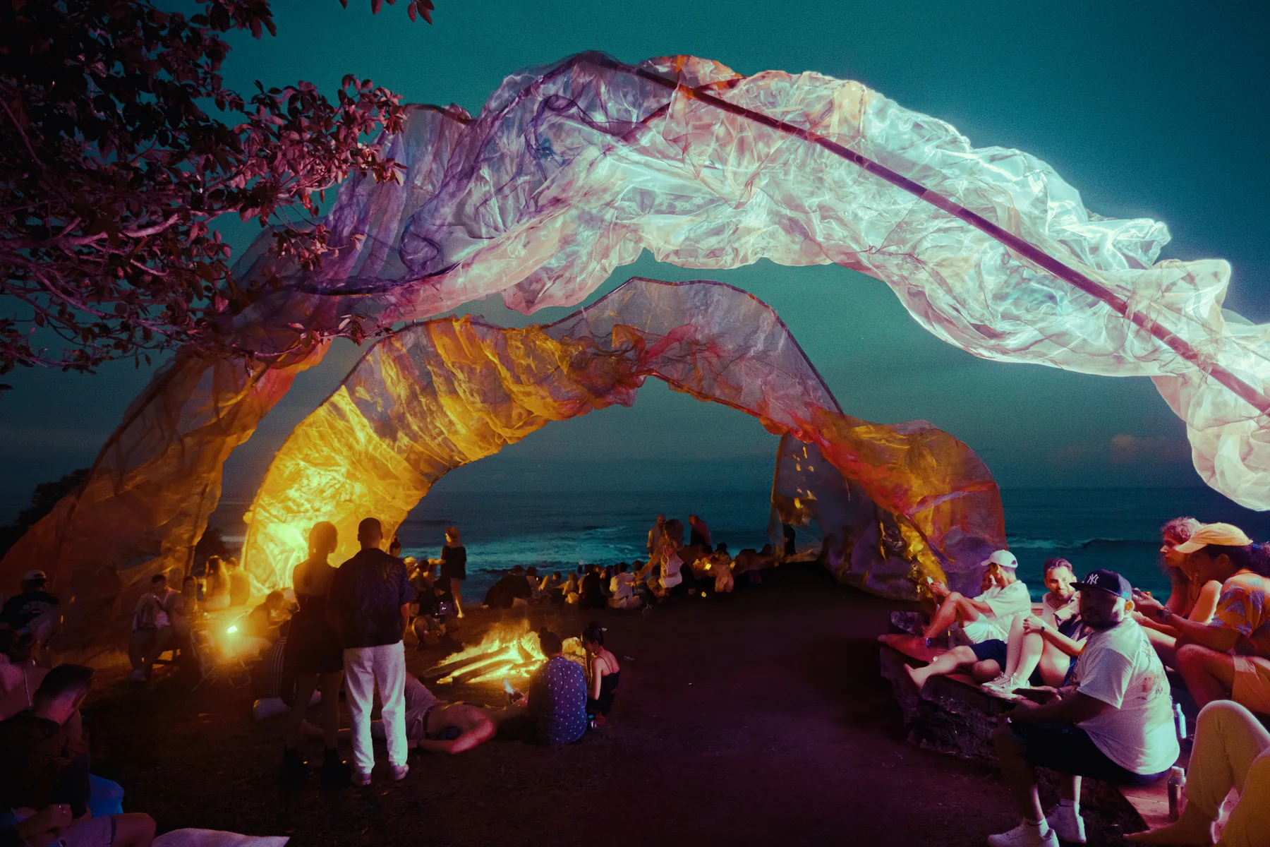 A fabric arch and a fire by the sea